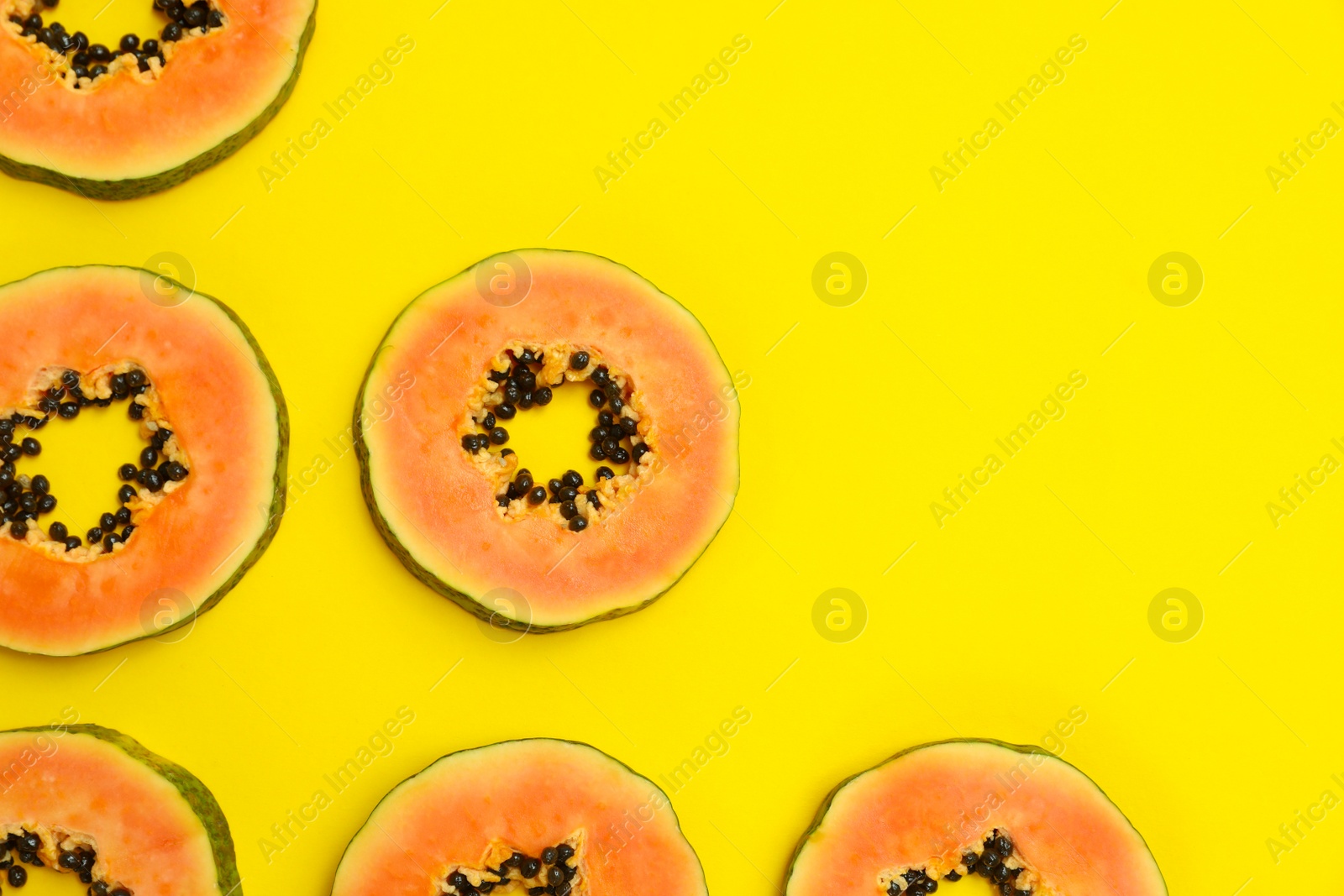 Photo of Flat lay composition with slices of papaya on yellow background, space for text