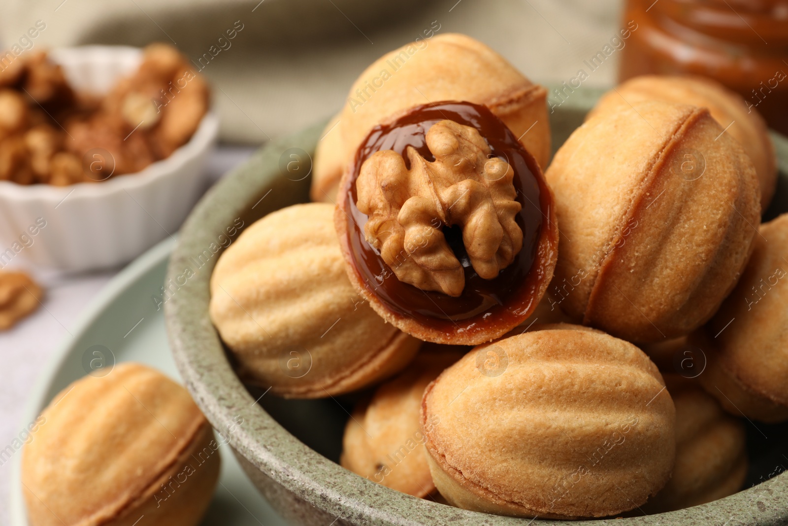 Photo of Delicious nut shaped cookies with boiled condensed milk in bowl, closeup