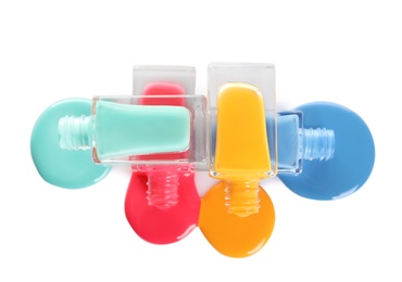 Photo of Spilled different nail polishes with bottles on white background, top view