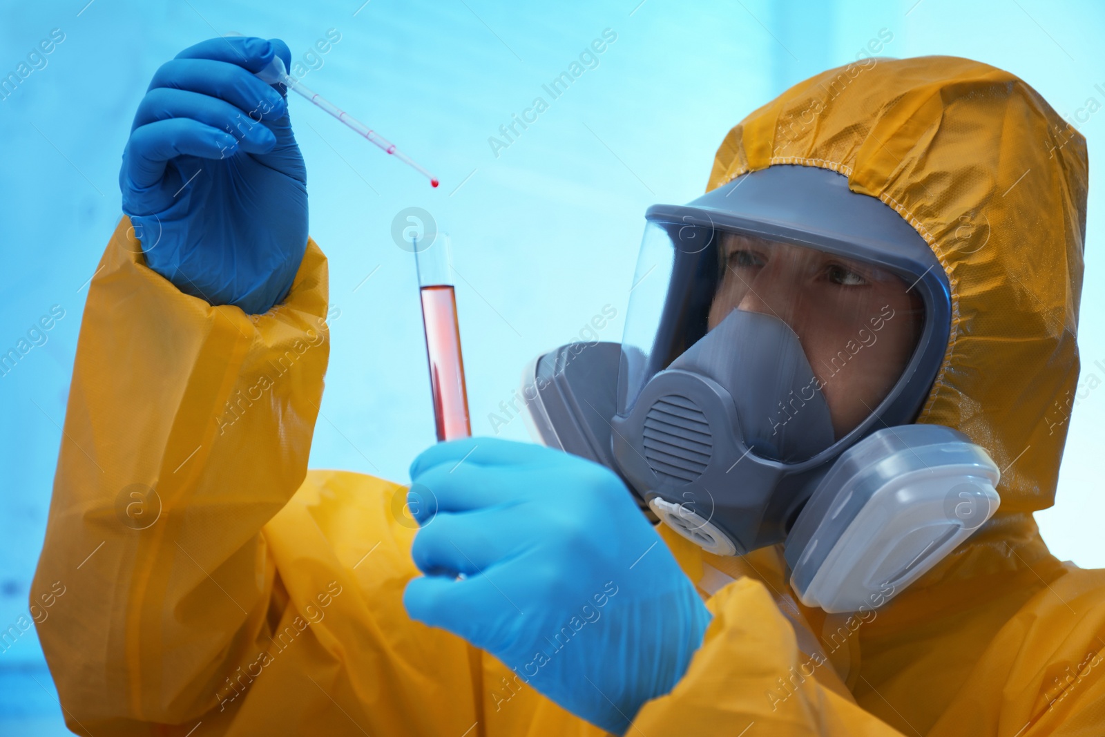 Photo of Scientist in chemical protective suit dripping reagent  into test tube at laboratory. Virus research