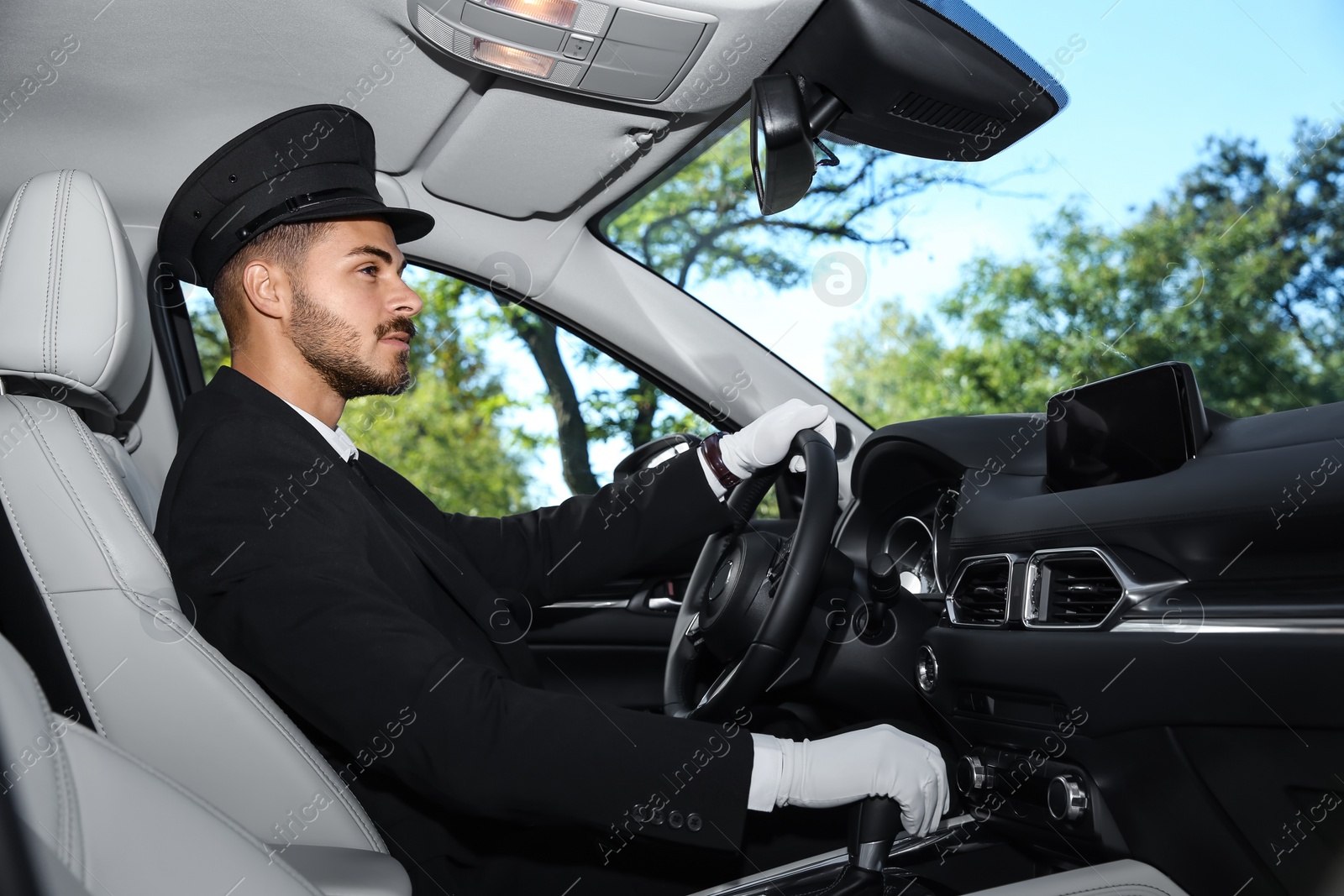 Photo of Young handsome driver in luxury car. Chauffeur service