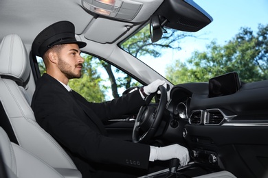 Photo of Young handsome driver in luxury car. Chauffeur service