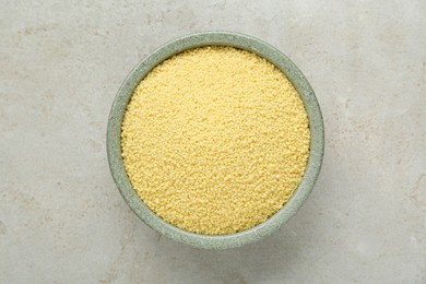 Bowl of raw couscous on light table, top view