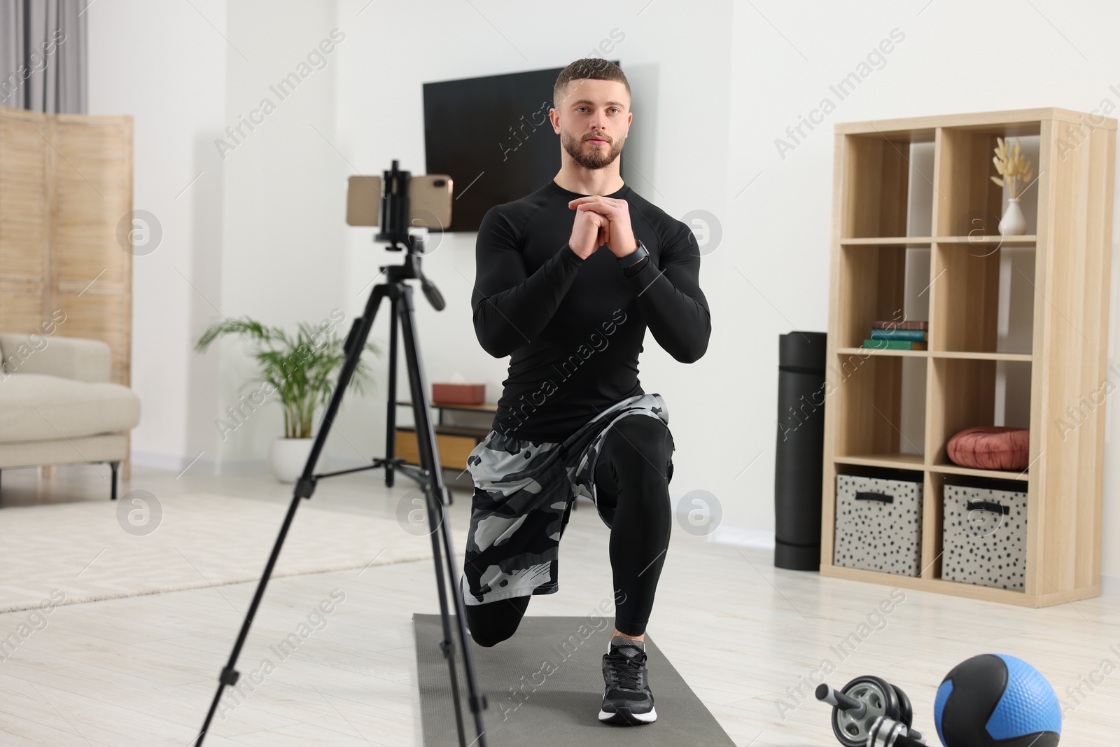 Photo of Trainer streaming online workout with phone at home