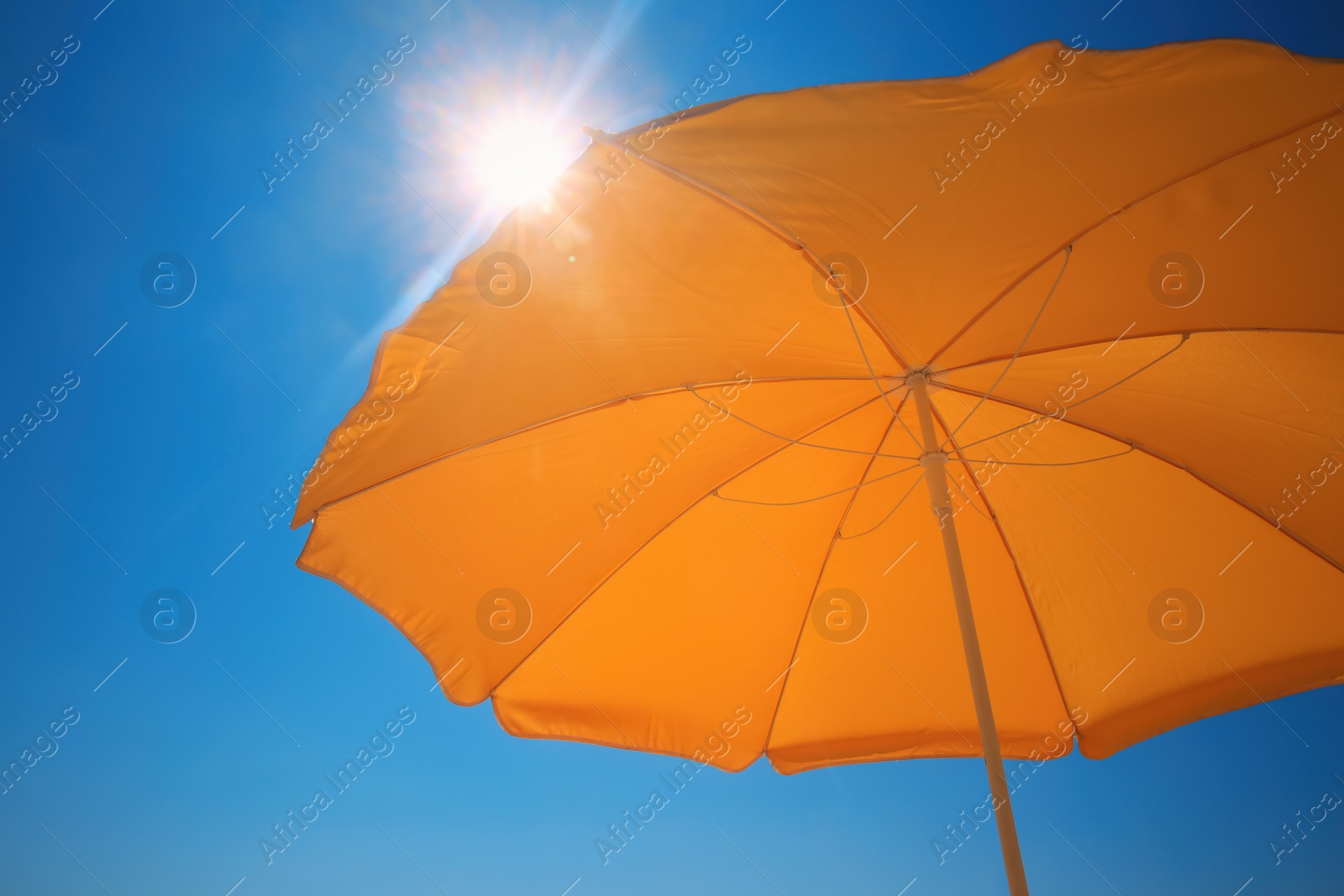 Photo of Orange beach umbrella against blue sky on sunny day