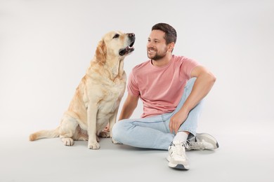 Photo of Man with adorable Labrador Retriever dog on light gray background. Lovely pet