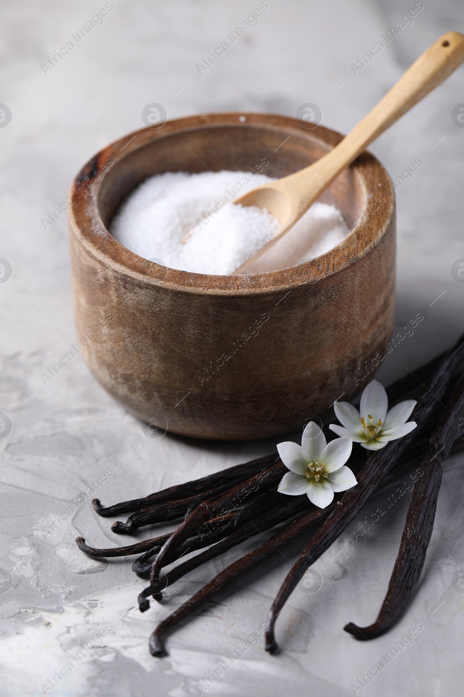 Photo of Vanilla pods, flowers and bowl with sugar on light textured table, closeup