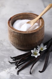 Photo of Vanilla pods, flowers and bowl with sugar on light textured table, closeup