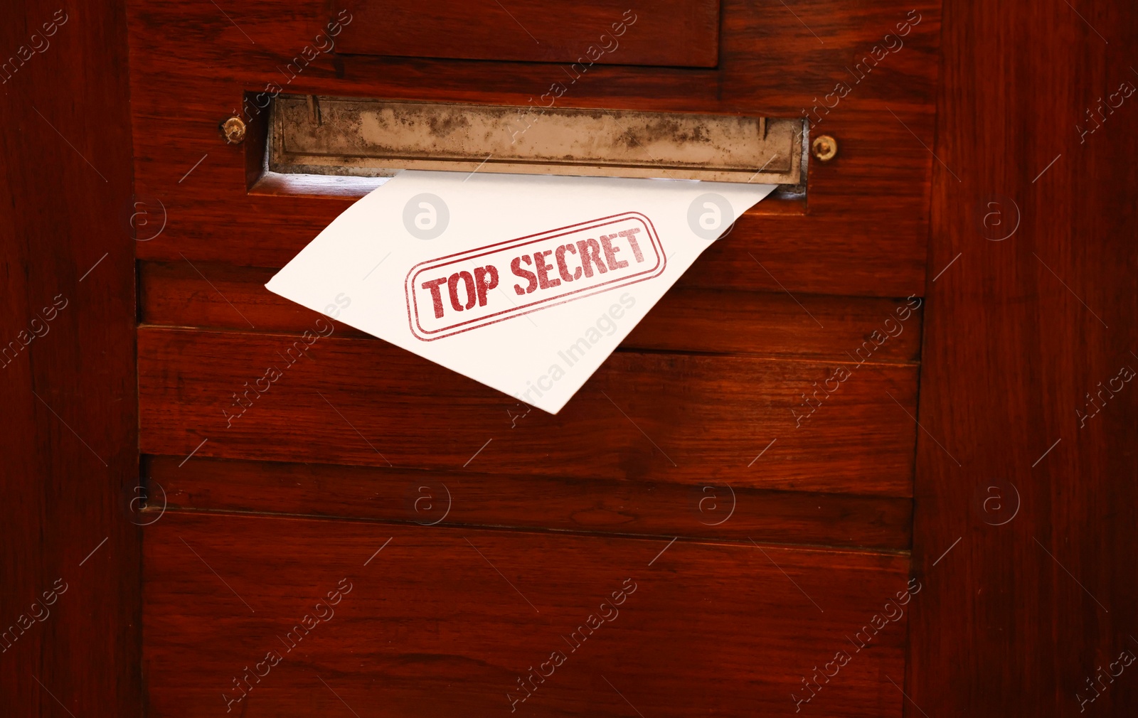 Image of Top Secret stamp. Mail slot with envelope in wooden door