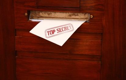 Top Secret stamp. Mail slot with envelope in wooden door