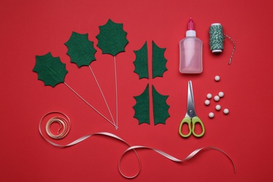 Set of instruments and materials for making mistletoe branch on red background, flat lay