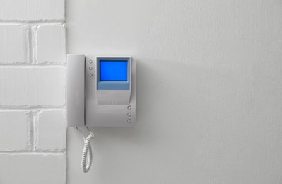 Photo of Modern intercom with camera installed on white wall