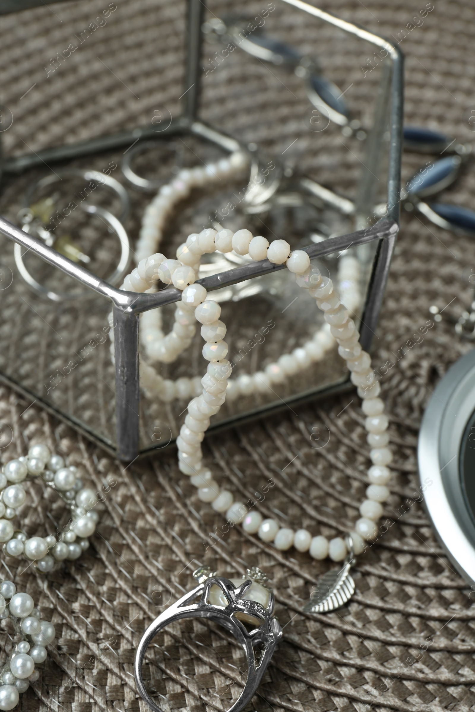 Photo of Different elegant jewelry on wicker mat, closeup