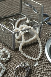 Different elegant jewelry on wicker mat, closeup