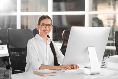Photo of Happy woman using modern computer at white desk in office