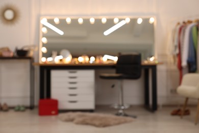 Photo of Blurred view of makeup room with stylish mirror, dressing table and chair