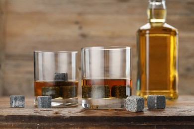 Photo of Whiskey stones and drink on wooden table, closeup