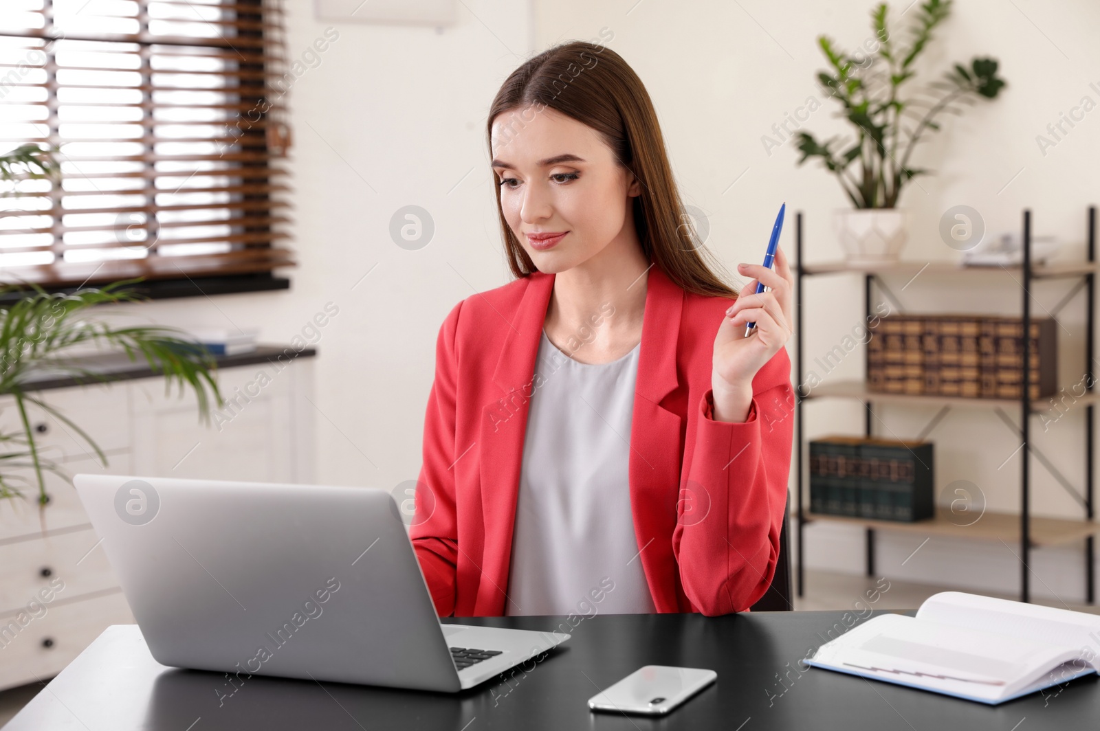 Photo of Young businesswoman using laptop at table in office