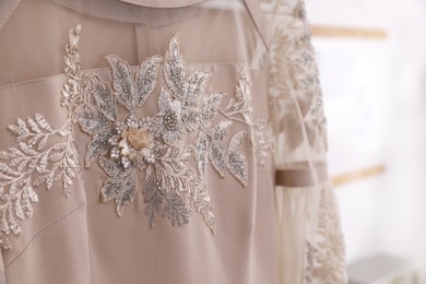 Photo of Beautiful beige dress with floral embroidery, closeup