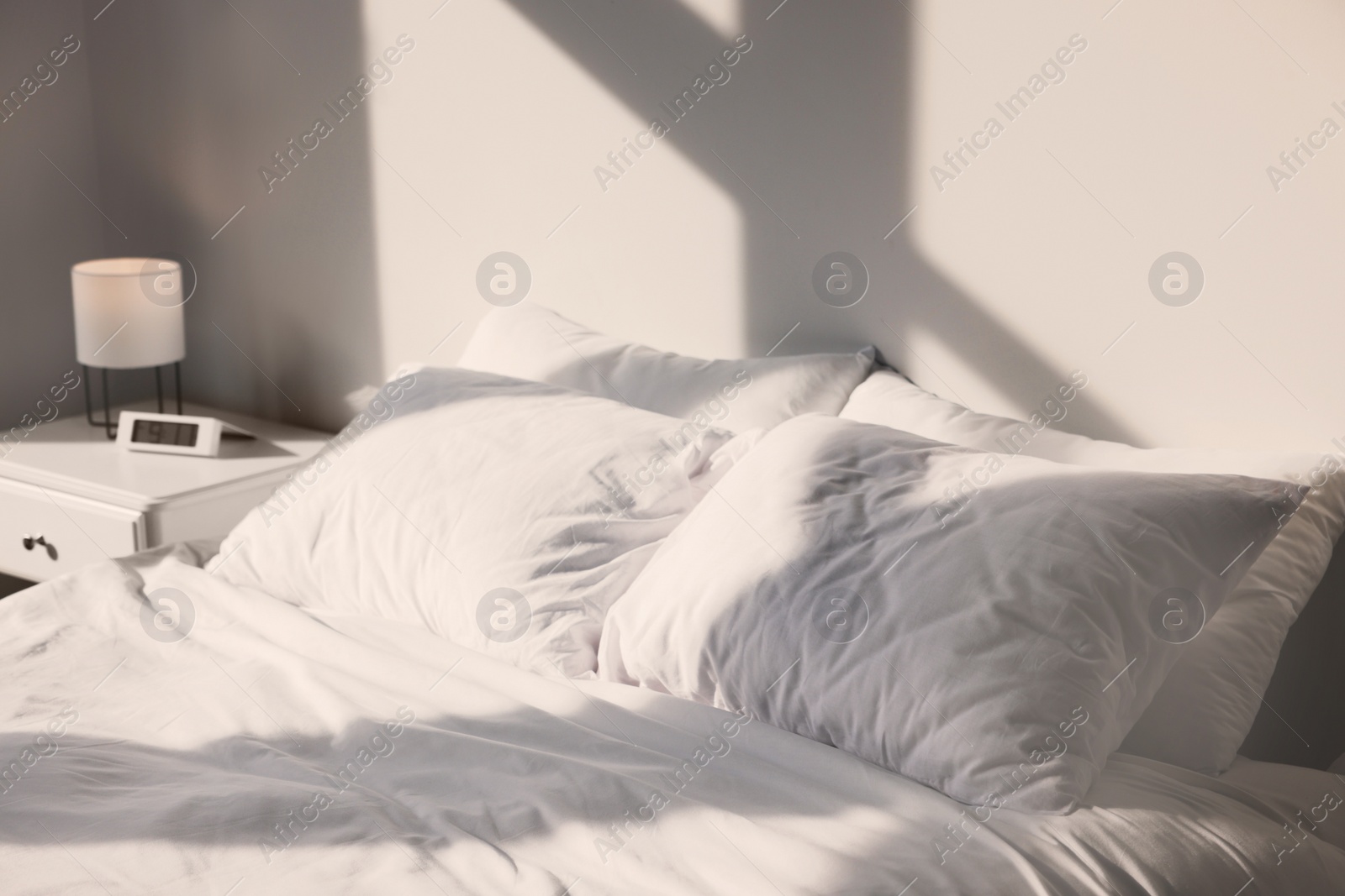 Photo of White soft pillows on bed in room