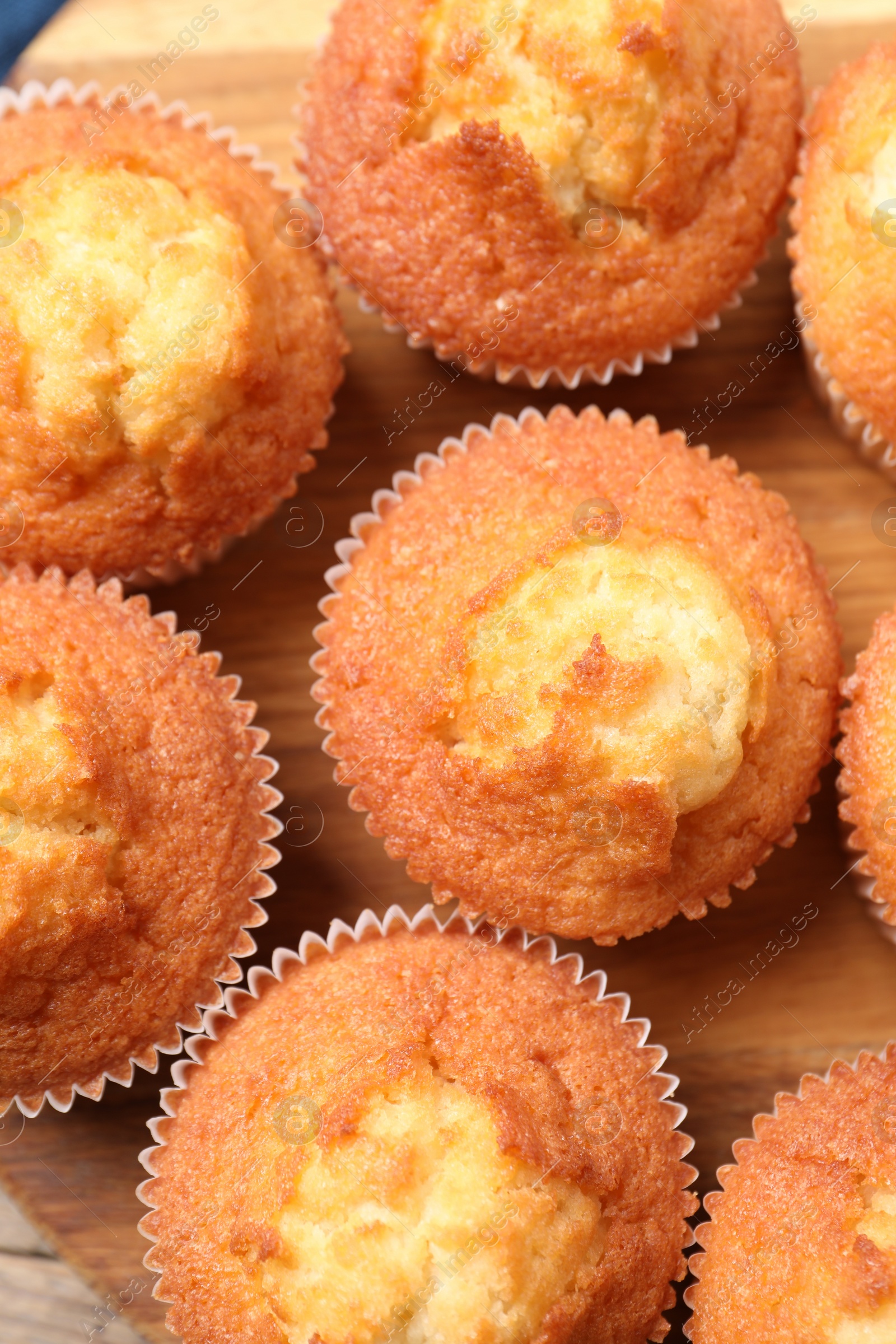 Photo of Delicious sweet muffins on wooden board, flat lay