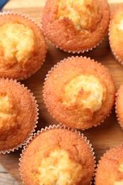 Delicious sweet muffins on wooden board, flat lay