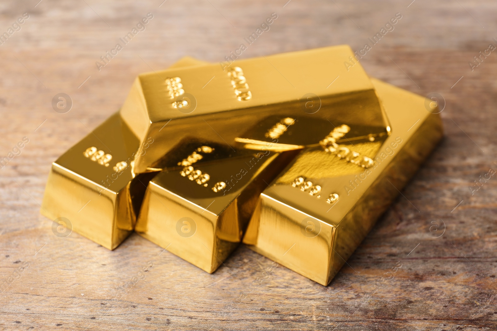 Photo of Precious shiny gold bars on wooden background