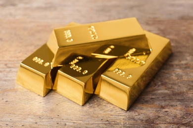 Precious shiny gold bars on wooden background