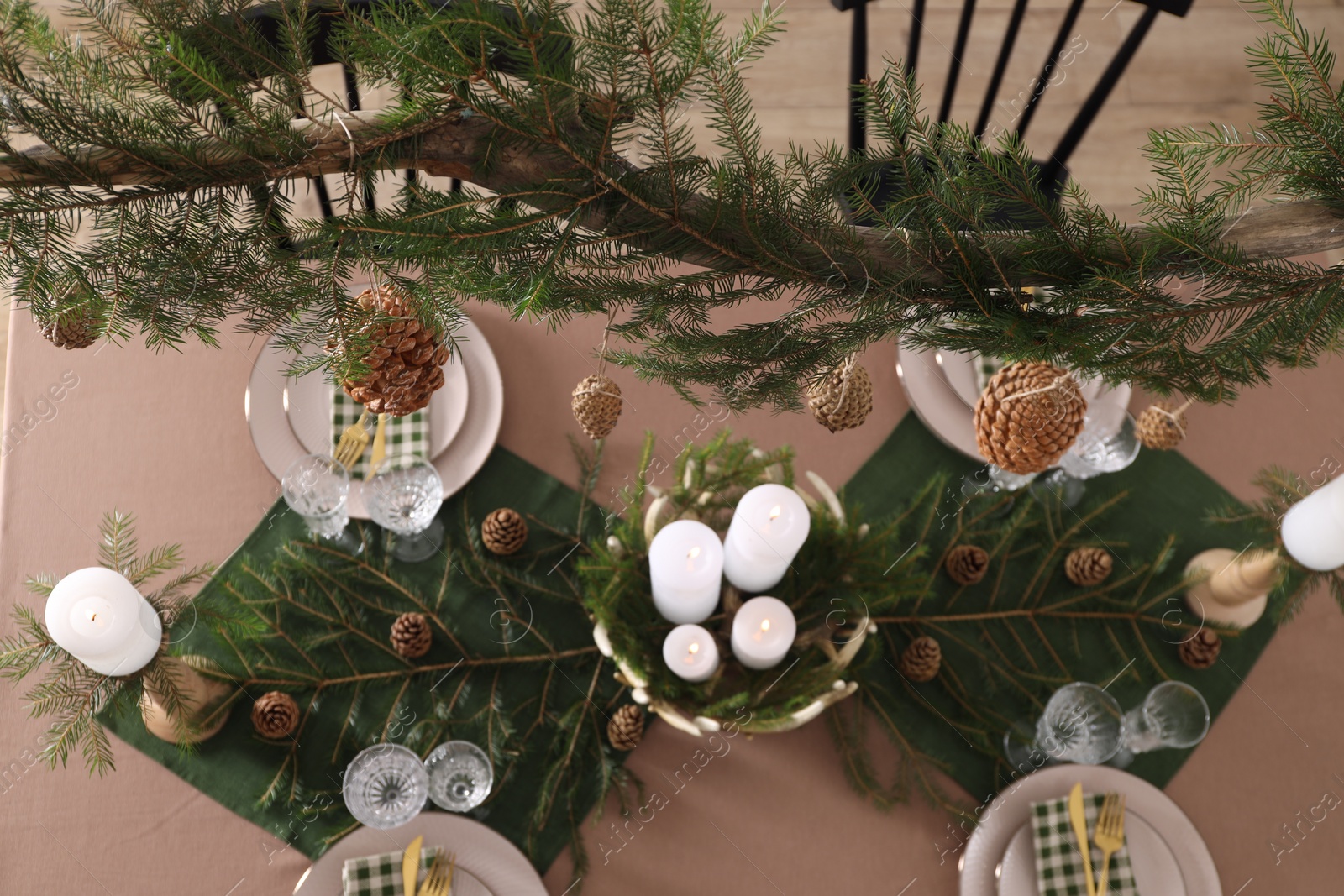 Photo of Christmas table setting with burning candles and other festive decor, above view