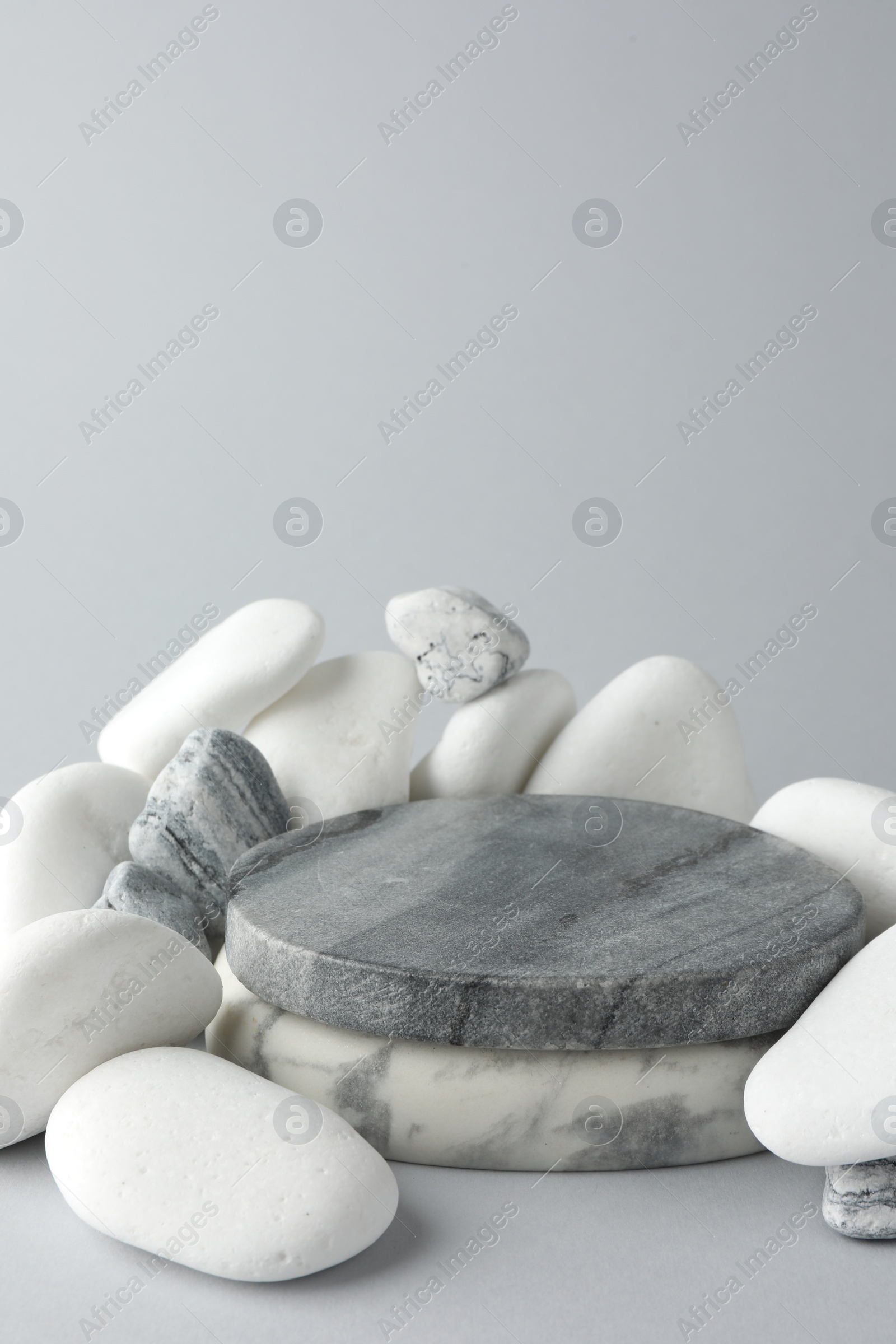 Photo of Presentation for product. Stone podium and pebbles on light grey background. Space for text