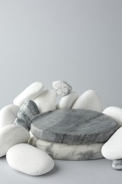 Presentation for product. Stone podium and pebbles on light grey background. Space for text