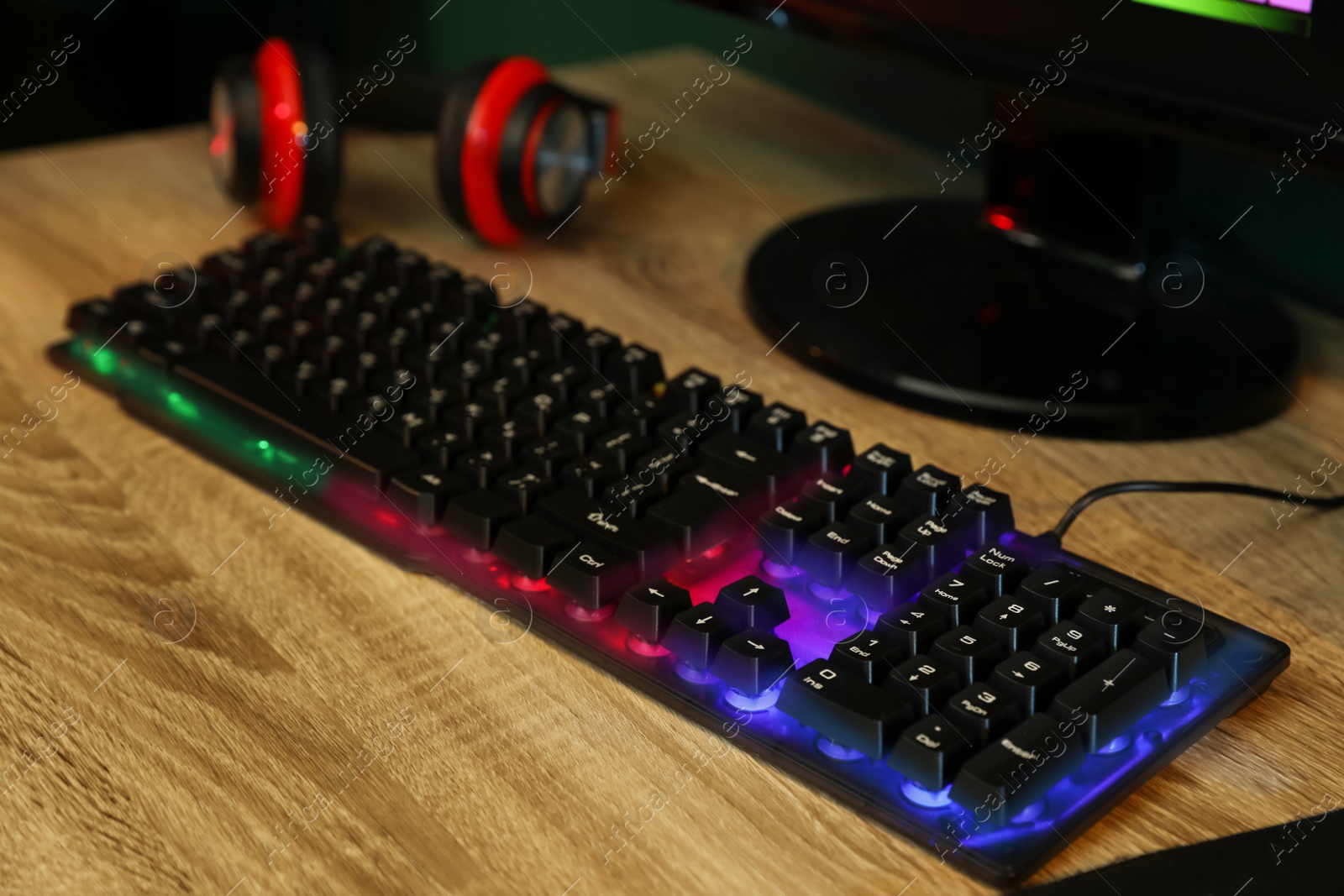 Photo of Modern RGB keyboard and computer on wooden table indoors