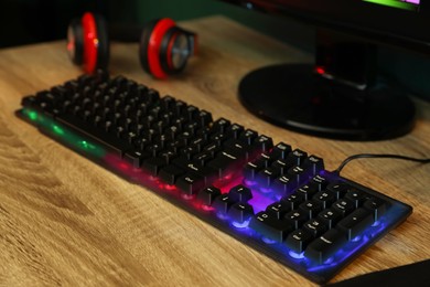 Modern RGB keyboard and computer on wooden table indoors