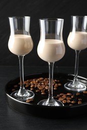 Photo of Coffee cream liqueur in glasses and beans on black wooden table