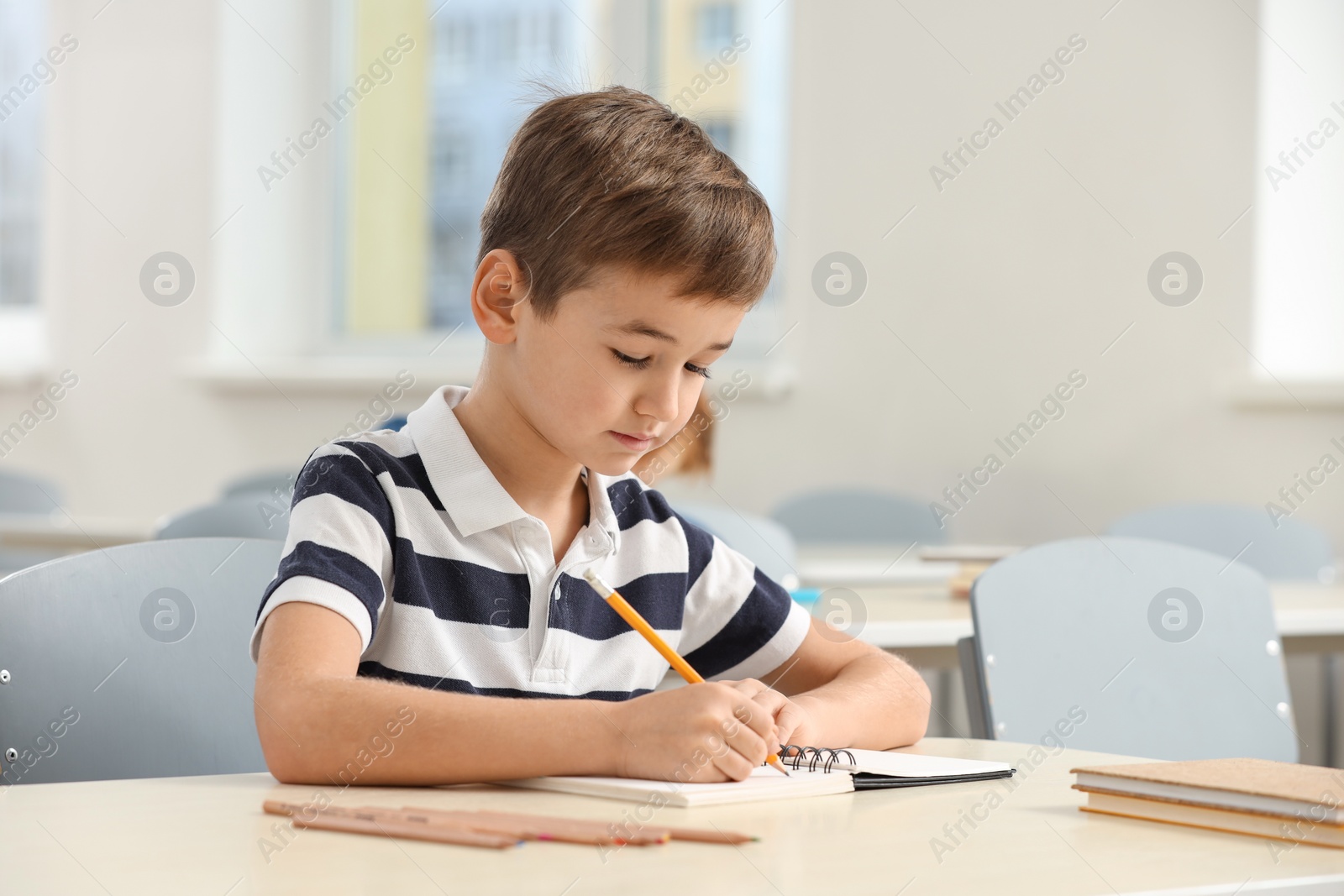 Photo of Cute little boy studying in classroom at school