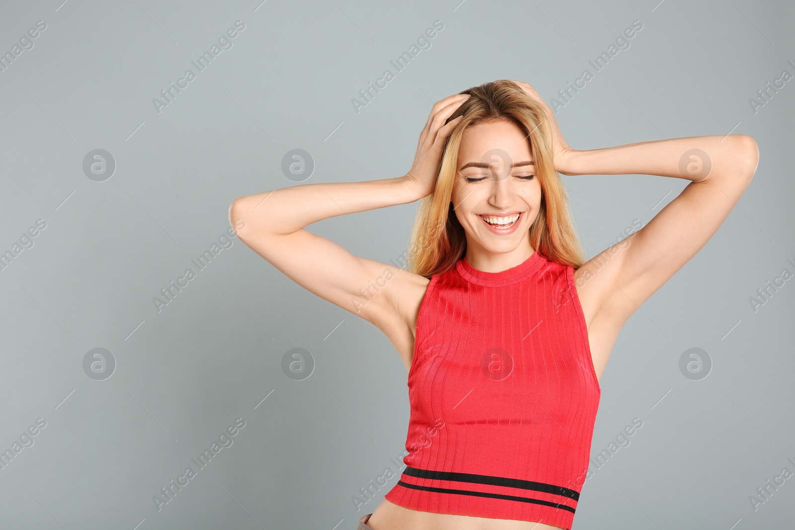 Photo of Portrait of beautiful young woman with blonde hair on grey background