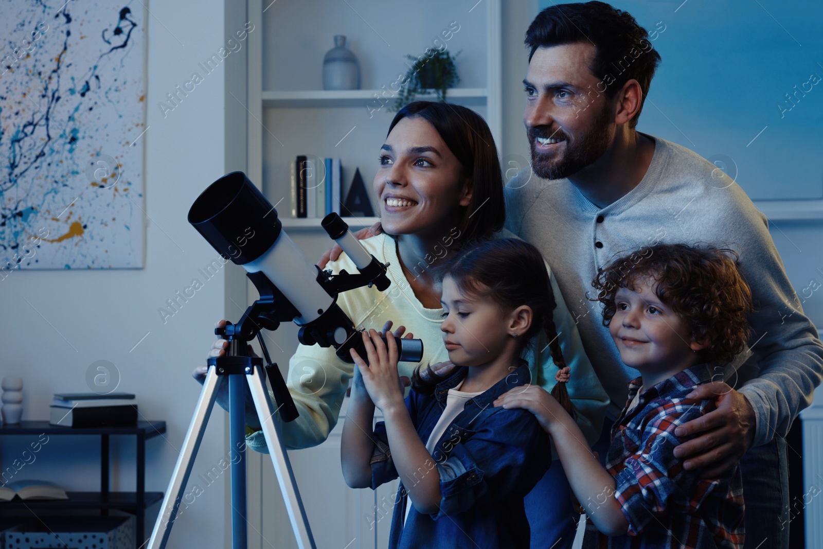 Photo of Happy family looking at stars through telescope in room