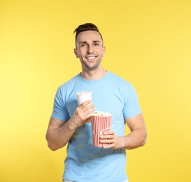 Man with popcorn and beverage during cinema show on color background