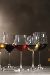 Photo of Glasses with different wines on table against dark background. Space for text