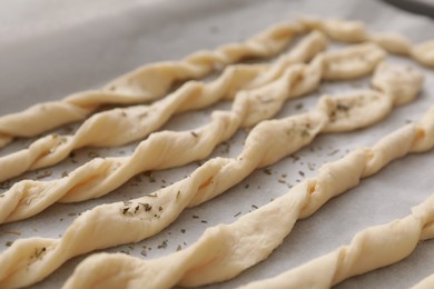 Homemade breadsticks with spices on baking sheet, closeup. Cooking traditional grissini