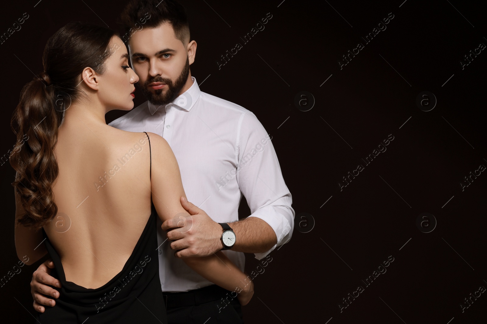 Photo of Handsome bearded man with sexy lady on dark background. Space for text