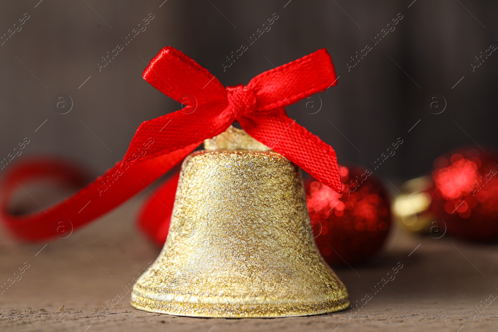 Photo of Bell with red bow on wooden table, closeup. Christmas decor