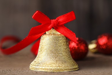 Photo of Bell with red bow on wooden table, closeup. Christmas decor