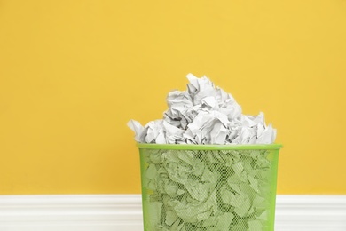 Photo of Metal bin with crumpled paper against color background