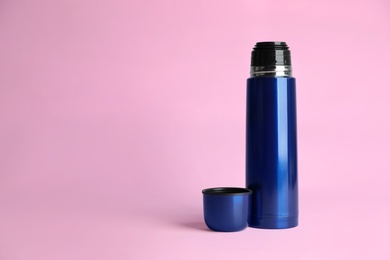 Photo of Stylish thermo bottle on pink background, space for text