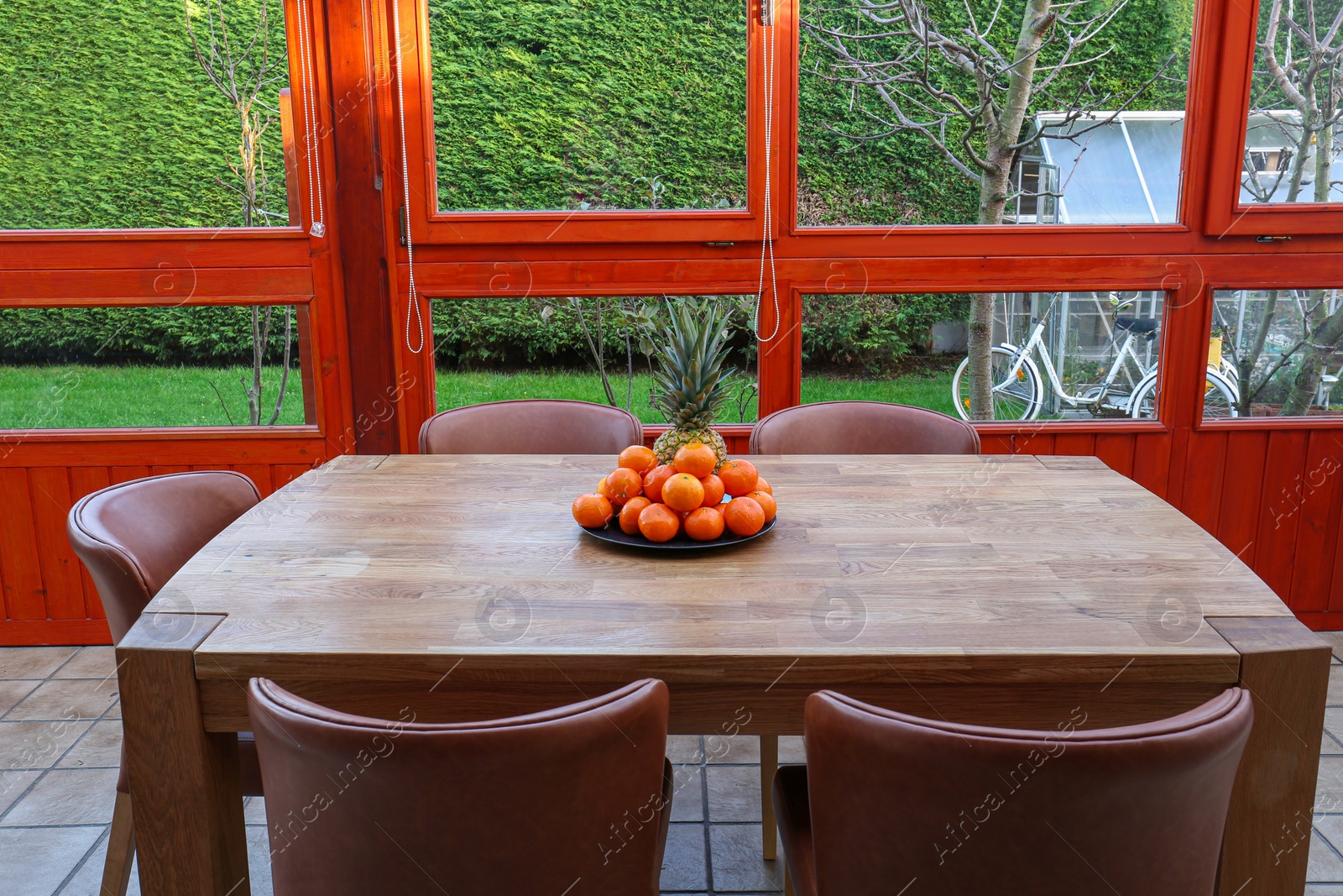 Photo of Wooden table with fruits and stylish chairs on terrace