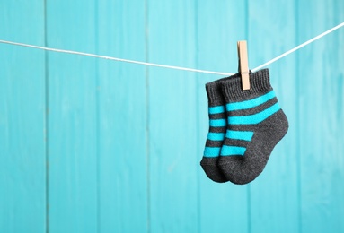 Baby socks on laundry line against color wooden background, space for text. Child accessories