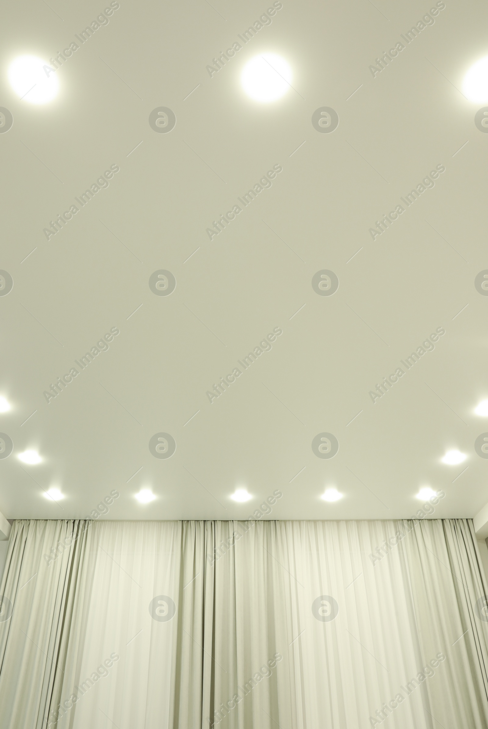 Photo of White stretch ceiling with spot lights in room