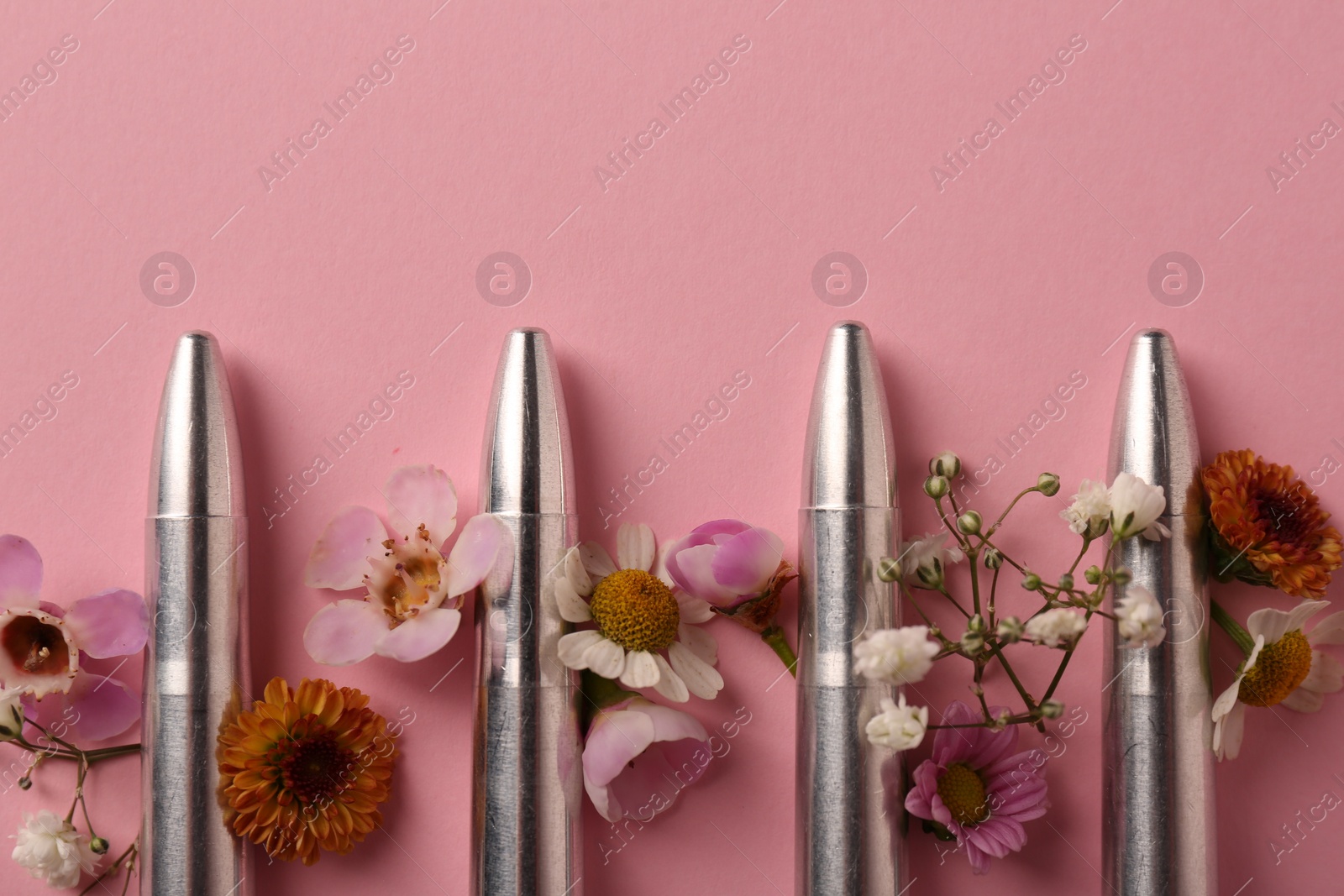 Photo of Bullets and beautiful flowers on pink background, flat lay. Space for text