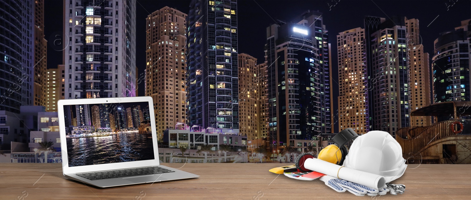 Image of Laptop with engineer equipment on table and night cityscape. Banner design